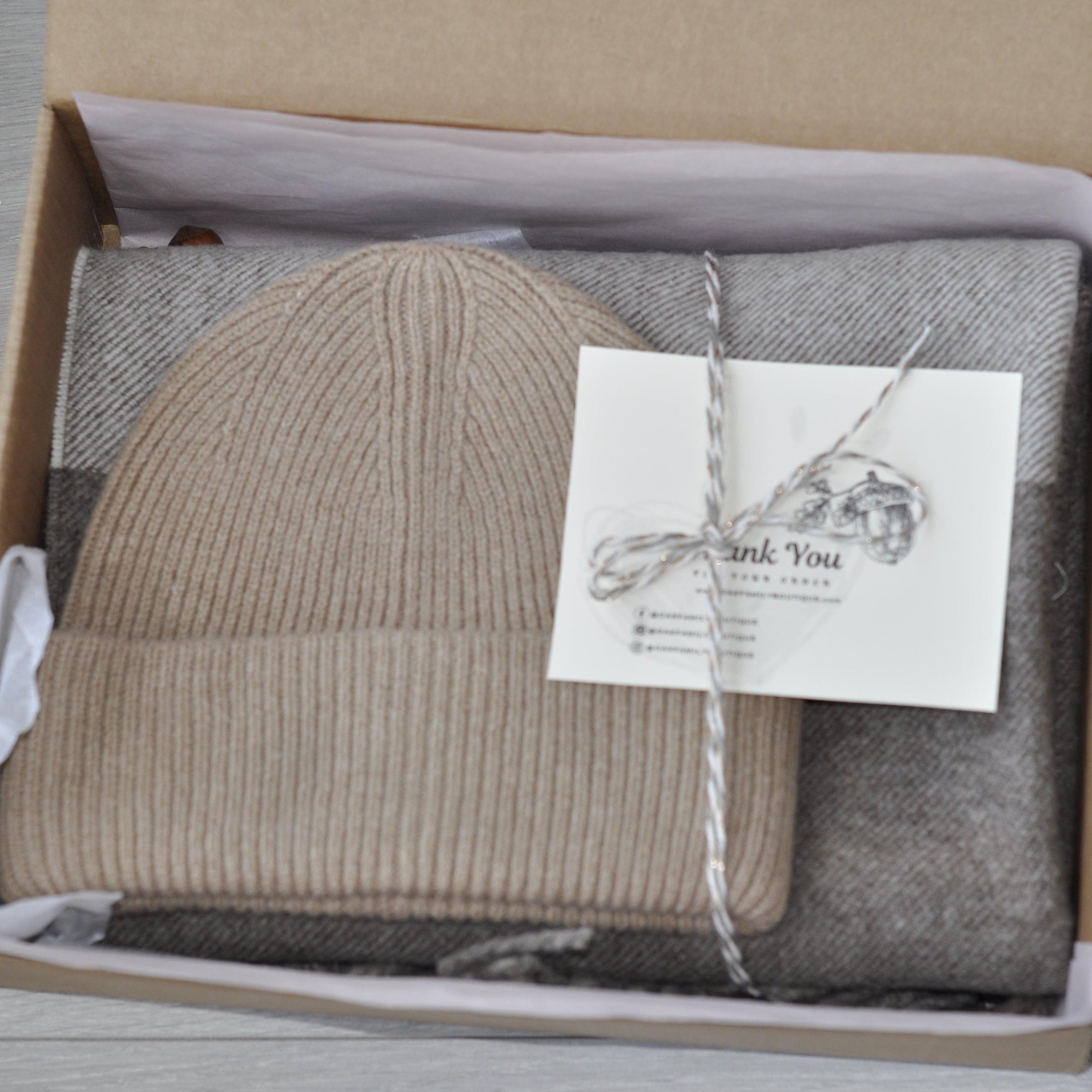 Knitted hat and scarf set in a box with a 'Thank You' card on a wooden surface