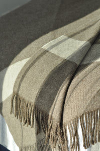 Close-up of a checkered fabric with fringes on a neutral background