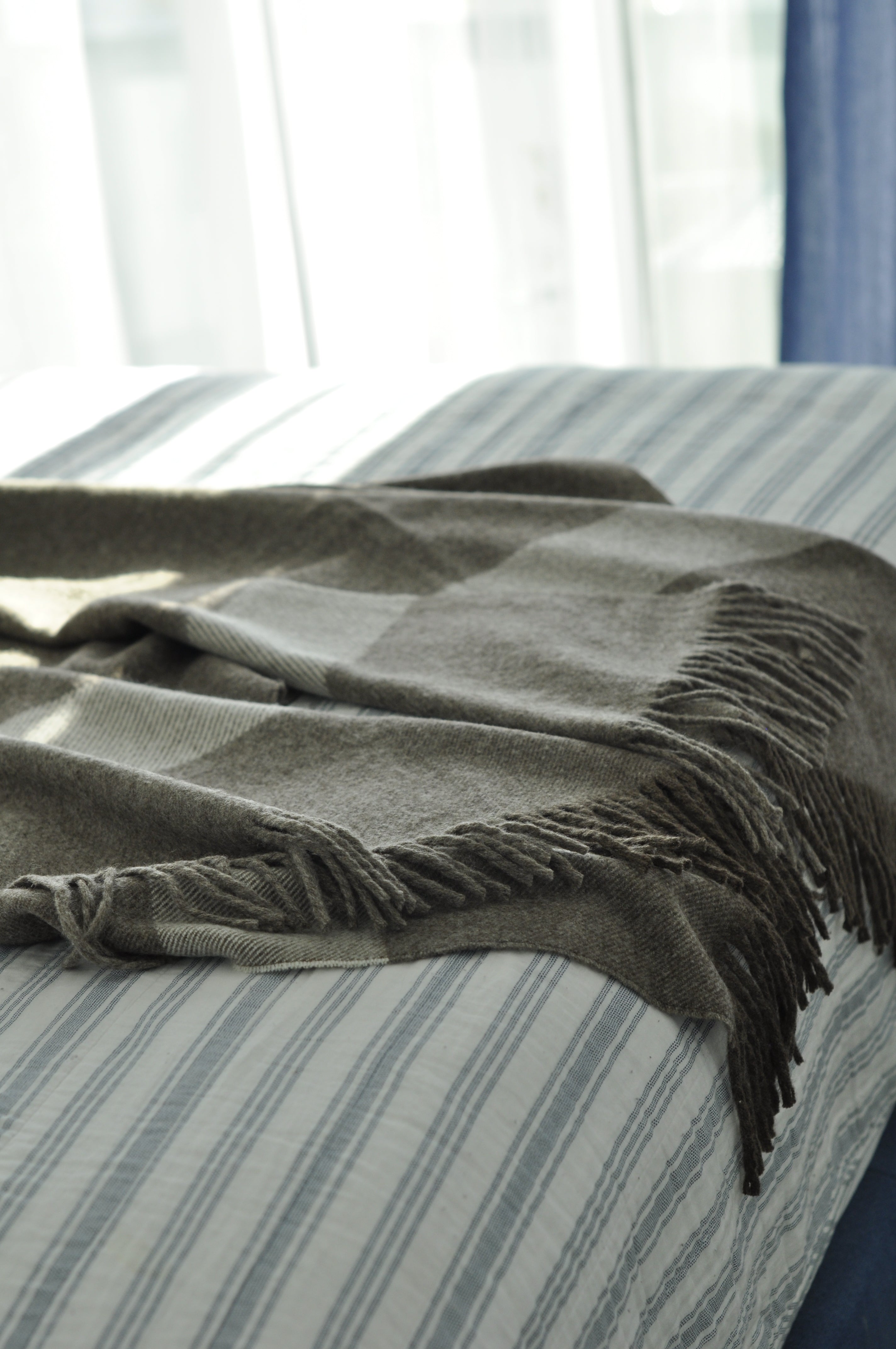 Plaid blanket with fringes draped over a striped chair
