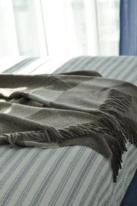 Plaid blanket with fringes draped over a striped chair