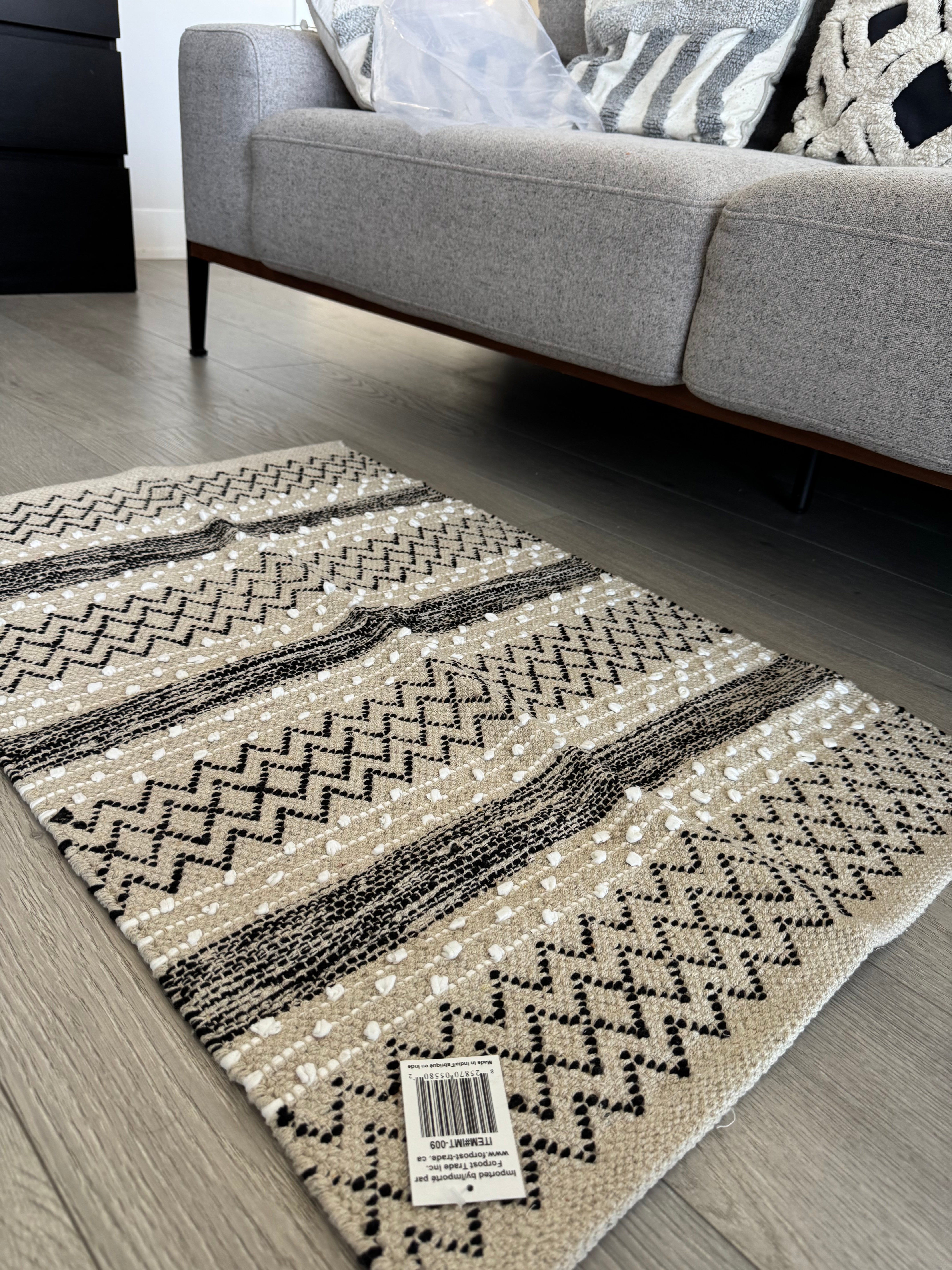 Patterned rug on a wooden floor with a gray sofa in the background