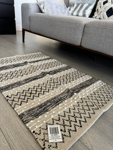 Patterned rug on a wooden floor with a gray sofa in the background