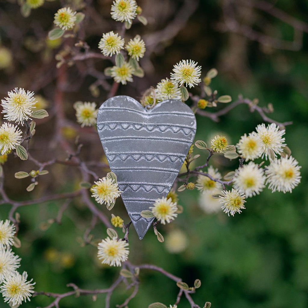 Heart-shaped decorative item on a branch with small white flowers