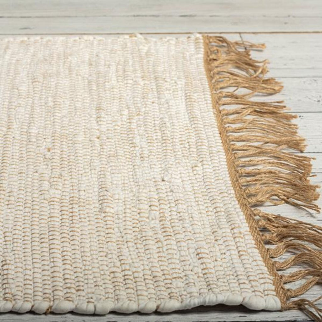 Woven rug with fringes on a wooden floor
