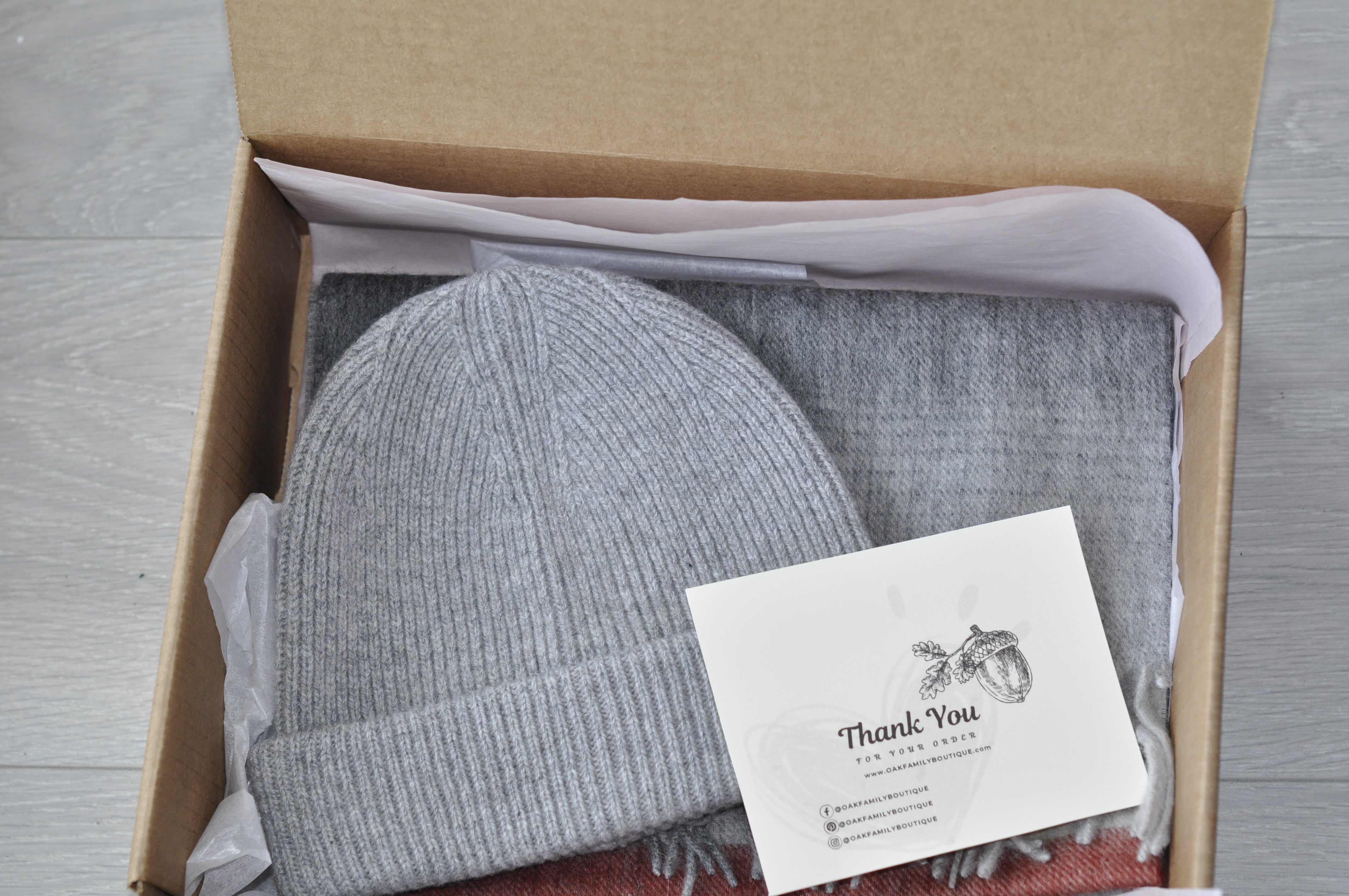 Gray knit beanie and scarf set in a box with a 'Thank You' card.