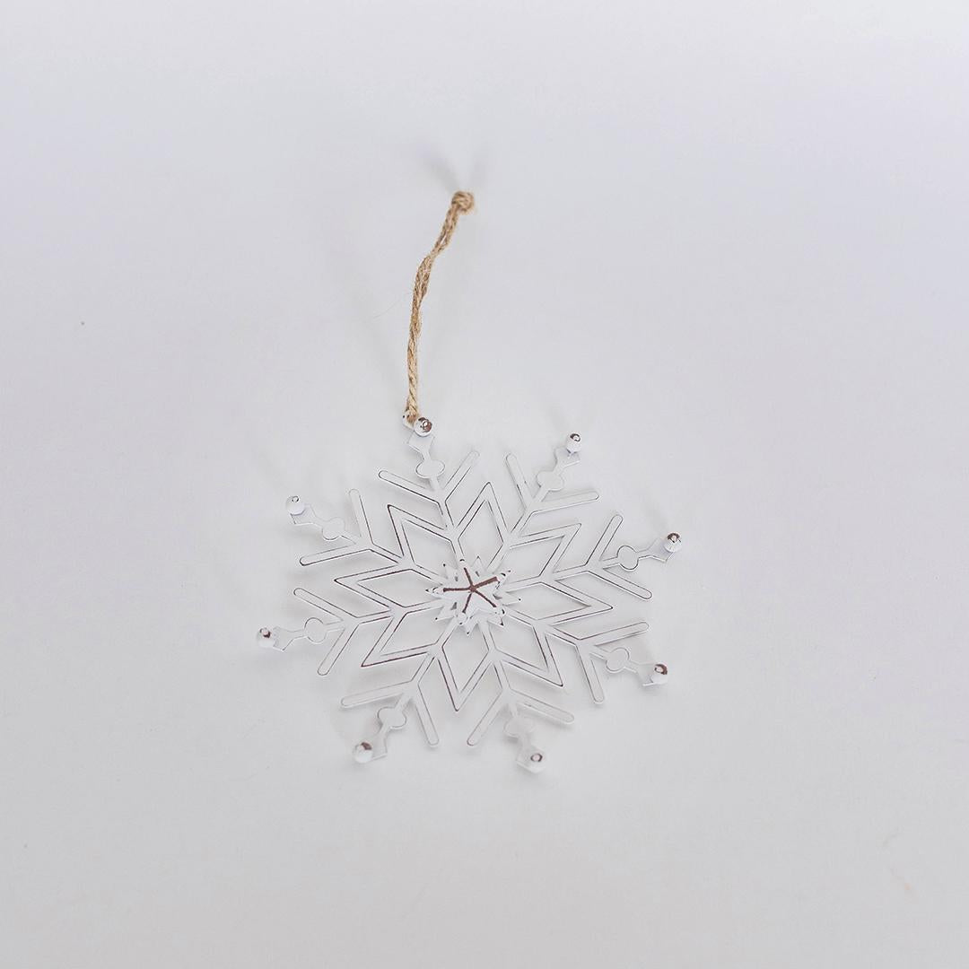 Clear snowflake ornament with a gold string on a light gray background