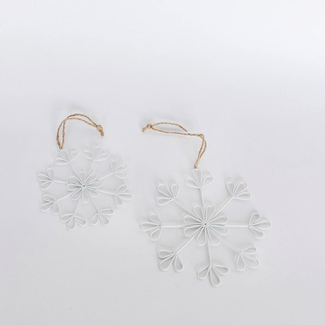 Two white snowflake-shaped decorations on a light gray background