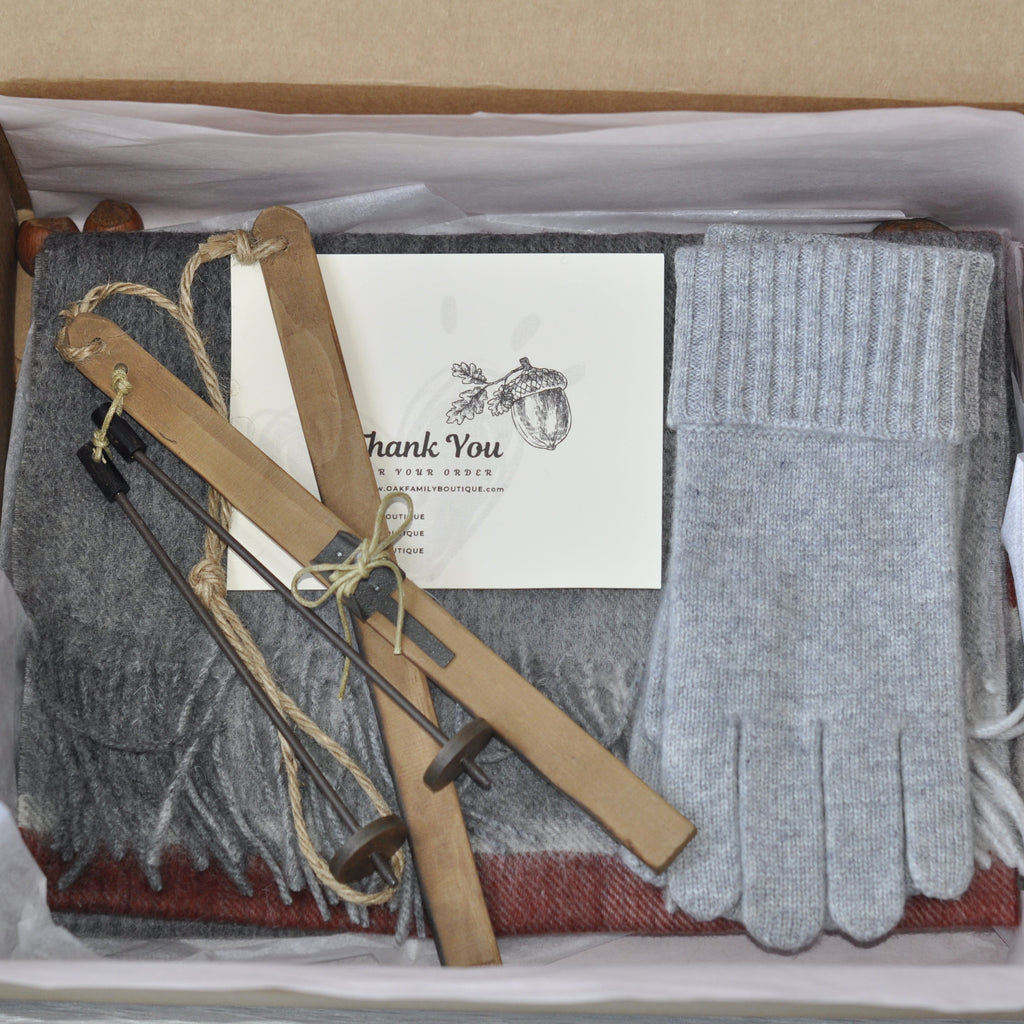 Gift set with scarf, gloves, and card in a box on a wooden surface