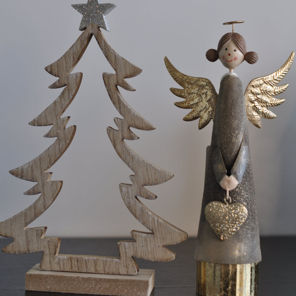 A metal figurine of an angel with gold wings and a heart-shaped ornament, standing on a wooden base.