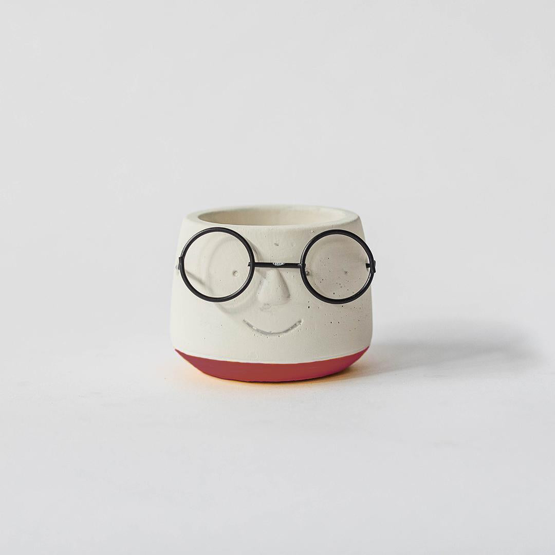 Ceramic face-shaped pot with glasses on a white background
