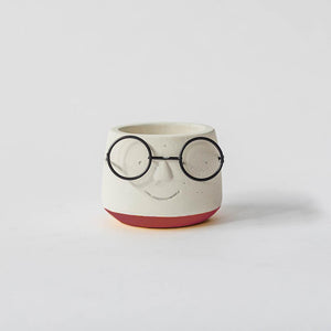 Ceramic face-shaped pot with glasses on a white background