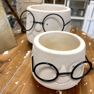 Two ceramic pots with black eyeglasses on a wooden surface, perfect gifts for teachers