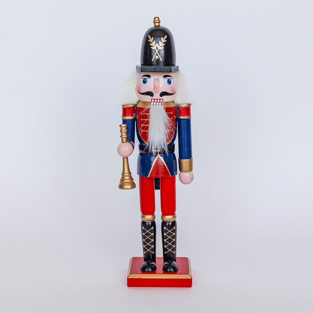Wooden nutcracker figurine with red uniform and black helmet on a light gray background