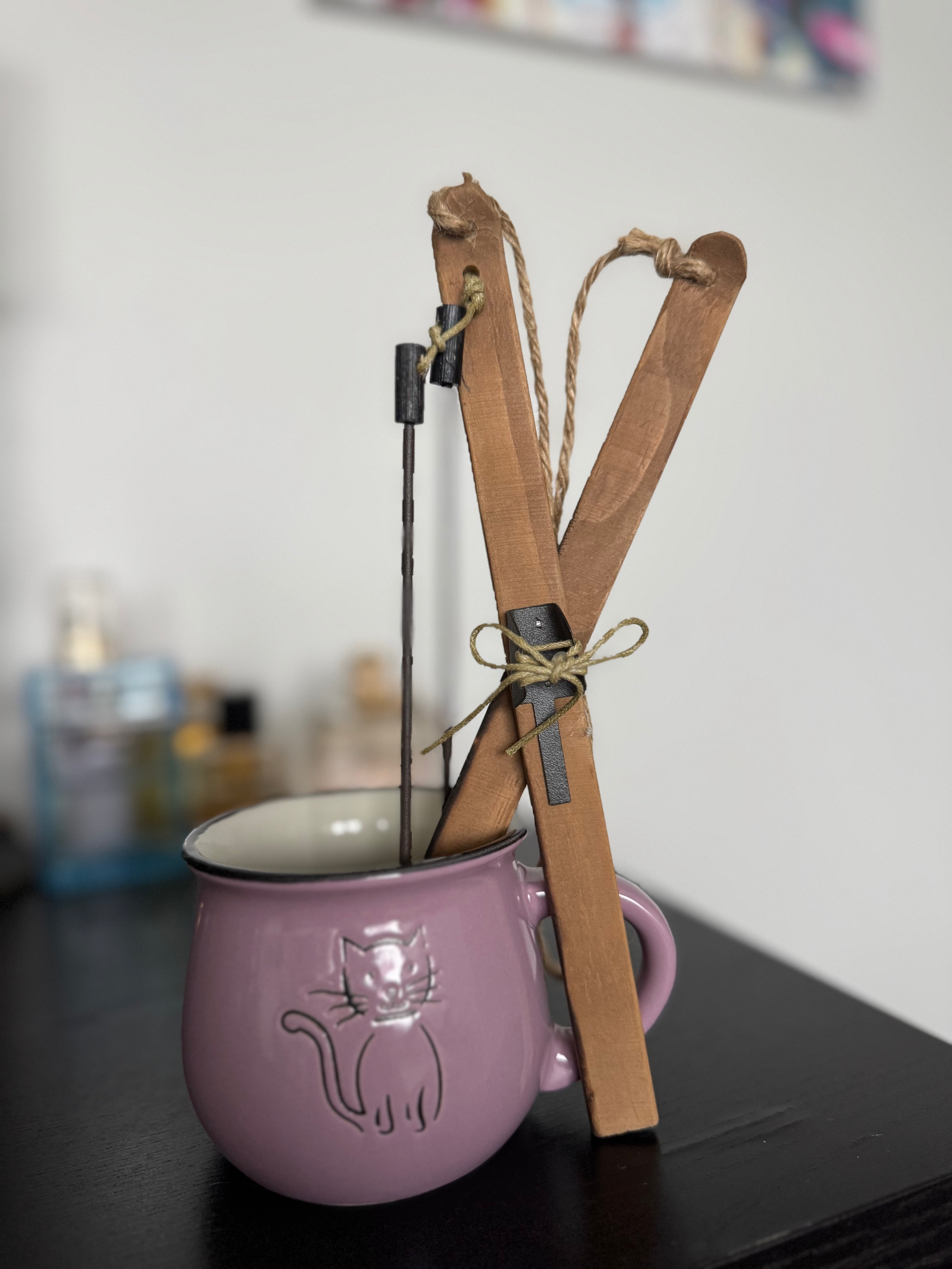 Purple mug with a cat design and a wooden catapult on a blurred background