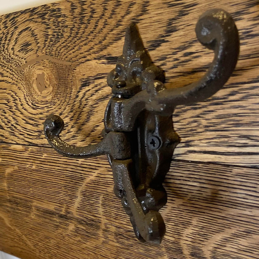A rustic brown finish cast iron triple hook mounted on a wooden surface.cast iron hooks canada