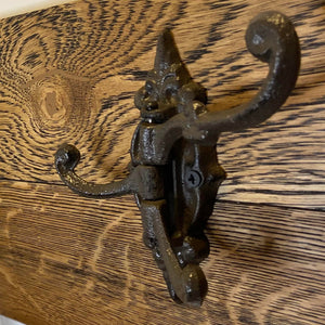 A rustic brown finish cast iron triple hook mounted on a wooden surface.cast iron hooks canada