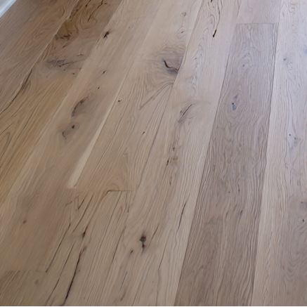 Living room with white furniture, wooden floor, and large windows.