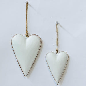 Two white metal heart-shaped ornaments with jute hanging loops, one larger than the other, displayed against a white background.