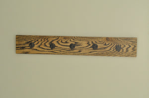 This vintage-style coat rack features five brown iron hooks mounted on a wooden panel