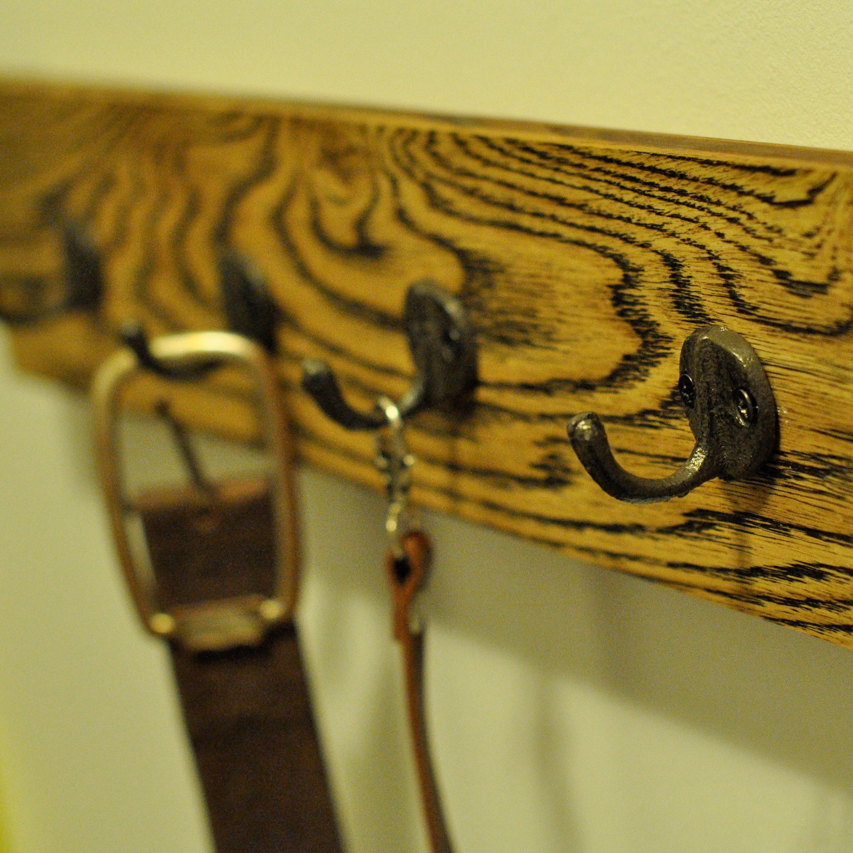 This vintage-style coat rack features five brown iron hooks mounted on a wooden panel